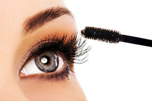 Woman applying mascara on her long eyelashes